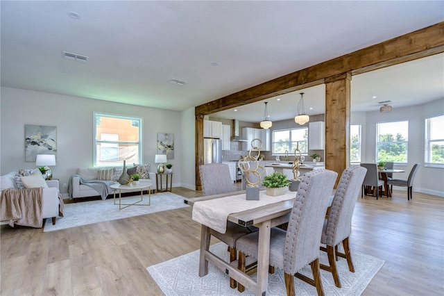 dining room featuring beam ceiling and light wood-type flooring