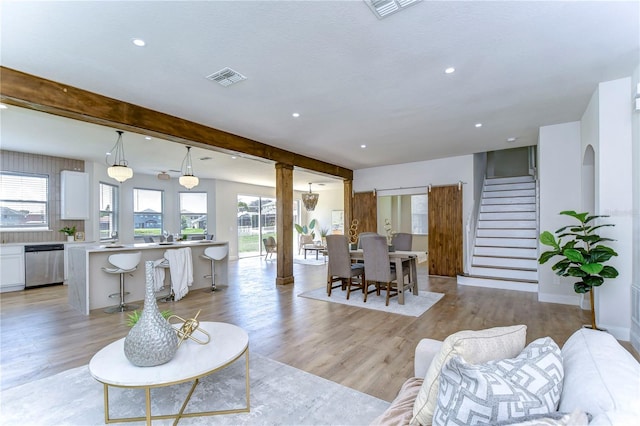 living room featuring a healthy amount of sunlight, beam ceiling, and light hardwood / wood-style floors