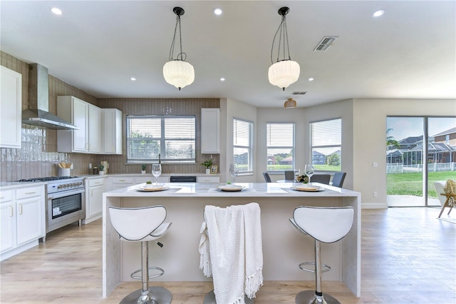 kitchen with white cabinets, a kitchen breakfast bar, oven, and wall chimney range hood