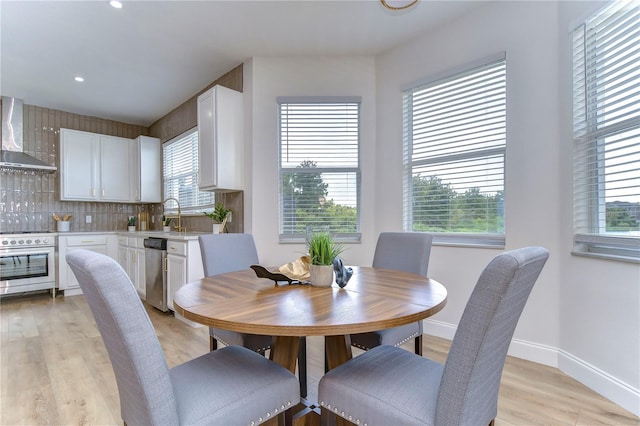 dining room featuring a healthy amount of sunlight, sink, and light hardwood / wood-style floors