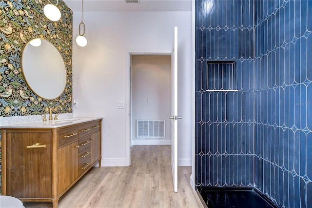 20131 Nob Oak Ave, Tampa, FL 33647 - bathroom with vanity, wood finished floors, tiled shower, baseboards, and wallpapered walls
