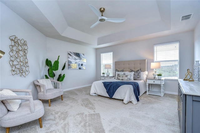 bedroom with ceiling fan, a raised ceiling, and light carpet