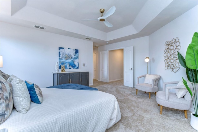 carpeted bedroom featuring ceiling fan and a raised ceiling