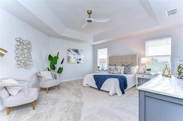 bedroom with ceiling fan, a tray ceiling, and light carpet