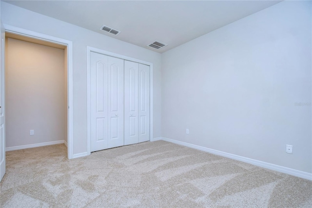 unfurnished bedroom with light carpet and a closet