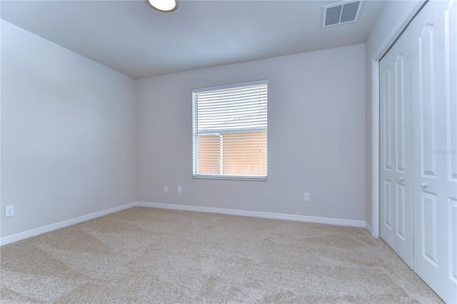 unfurnished bedroom with light colored carpet and a closet