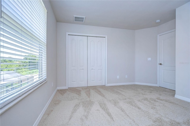 unfurnished bedroom featuring a closet and light carpet