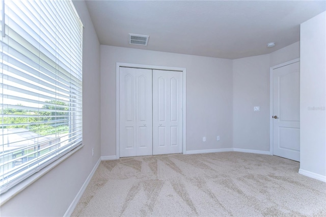 unfurnished bedroom with light colored carpet and a closet