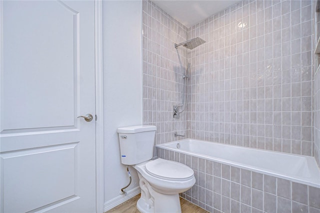 bathroom with wood-type flooring, toilet, and tiled shower / bath