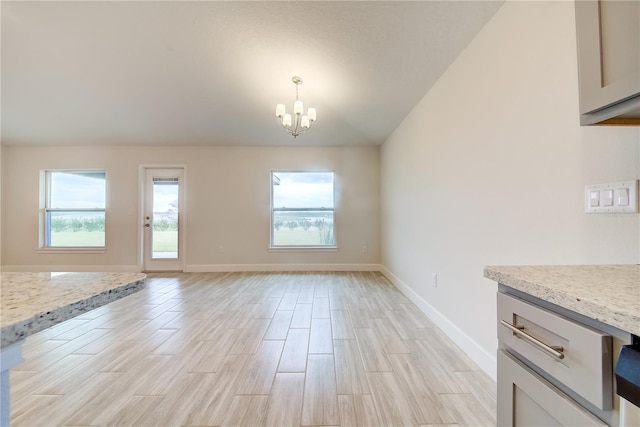 unfurnished living room featuring a chandelier and light wood-type flooring