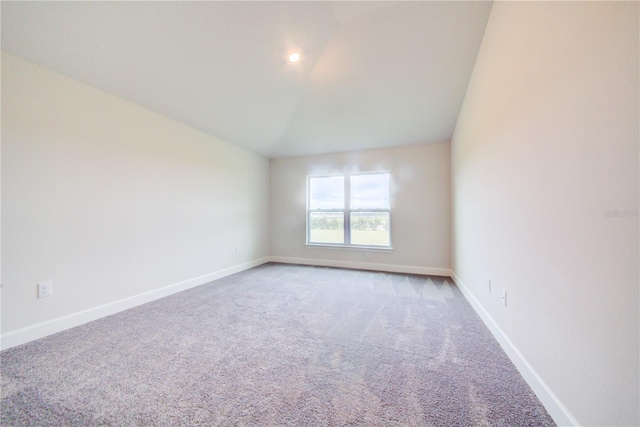 carpeted empty room with vaulted ceiling