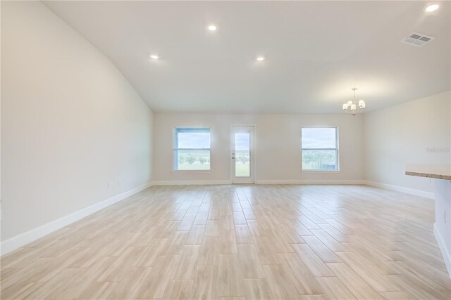 spare room with light wood-type flooring and a notable chandelier