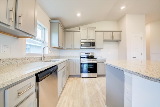 kitchen featuring stainless steel appliances, light stone countertops, sink, and gray cabinetry