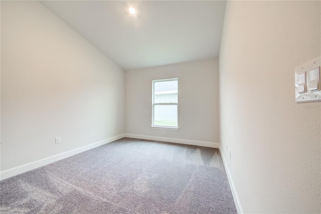 carpeted spare room featuring lofted ceiling