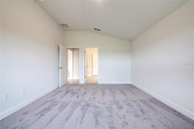 spare room with light colored carpet and lofted ceiling