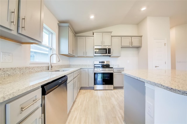 kitchen with gray cabinetry, sink, stainless steel appliances, and vaulted ceiling