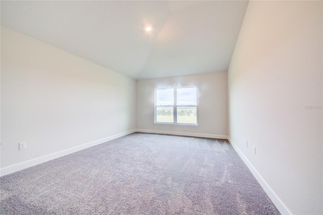 unfurnished room featuring lofted ceiling and light colored carpet