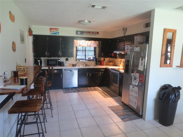 kitchen with light tile patterned flooring, sink, appliances with stainless steel finishes, and range hood