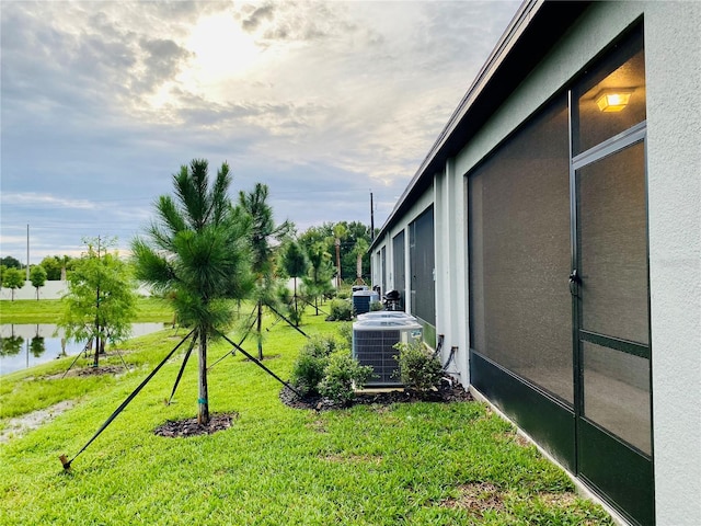 view of yard featuring central air condition unit and a water view