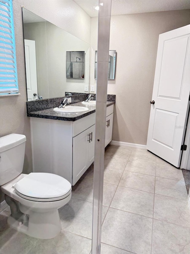 bathroom featuring vanity, toilet, a textured ceiling, and tile patterned flooring