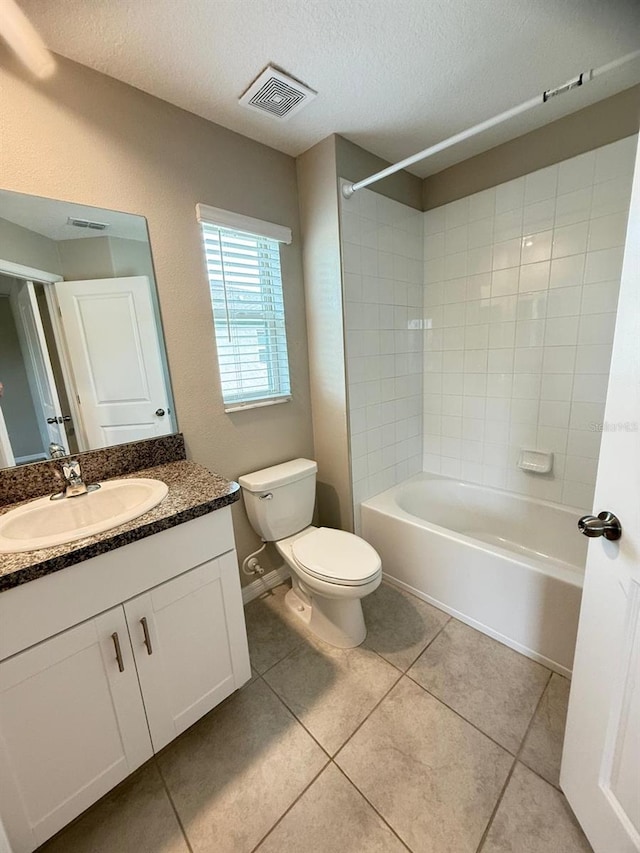 full bathroom featuring a textured ceiling, toilet, vanity, tiled shower / bath combo, and tile patterned flooring