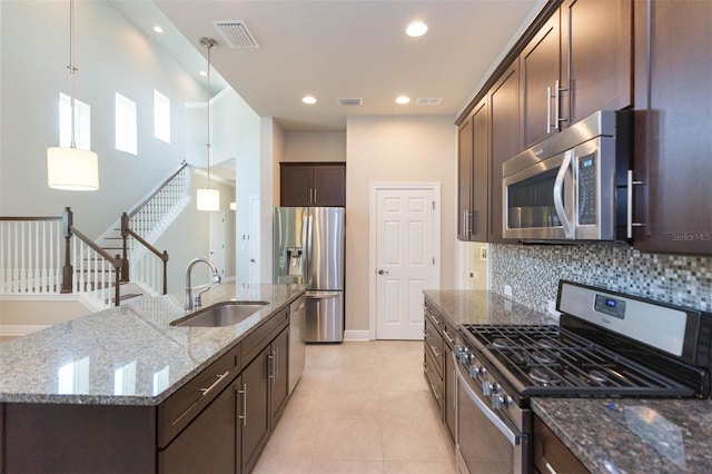 kitchen featuring stainless steel appliances, sink, pendant lighting, backsplash, and light tile patterned floors