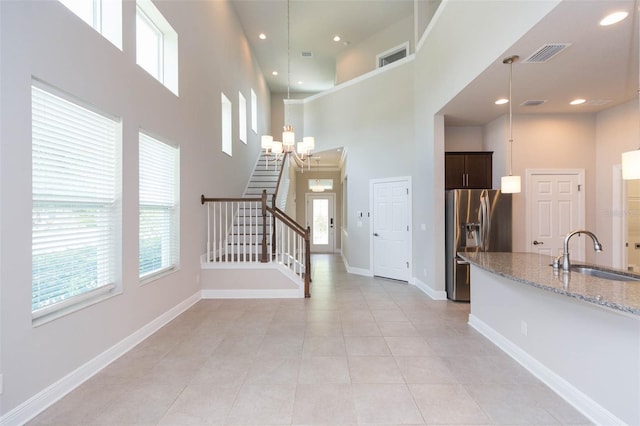 interior space featuring sink, light tile patterned flooring, an inviting chandelier, and a towering ceiling