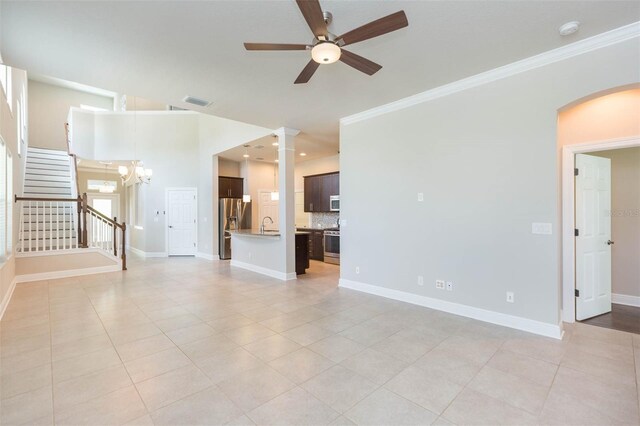 unfurnished living room with ceiling fan with notable chandelier, ornamental molding, and light tile patterned floors