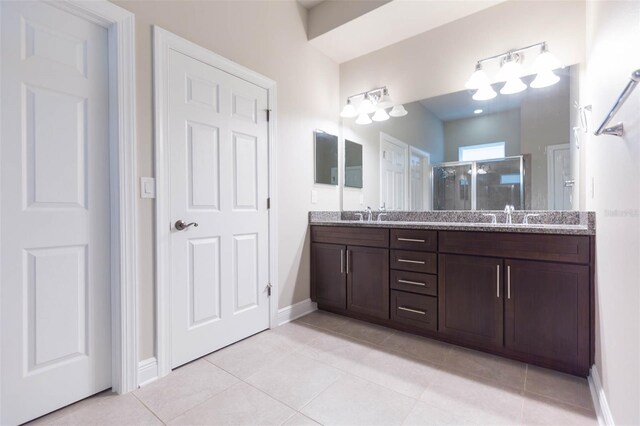 bathroom featuring a shower with shower door, tile patterned flooring, and double sink vanity