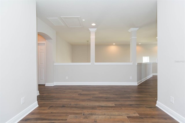 empty room featuring dark hardwood / wood-style flooring and ornate columns