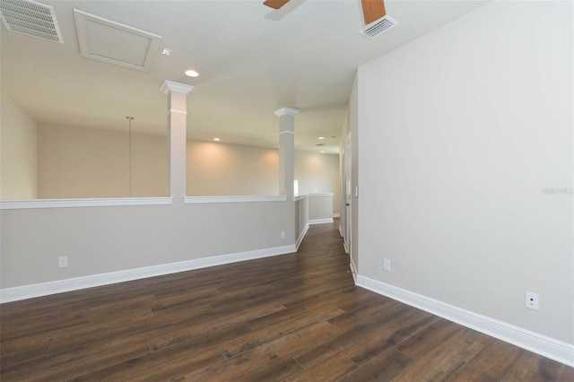 spare room featuring decorative columns, ceiling fan, and dark wood-type flooring