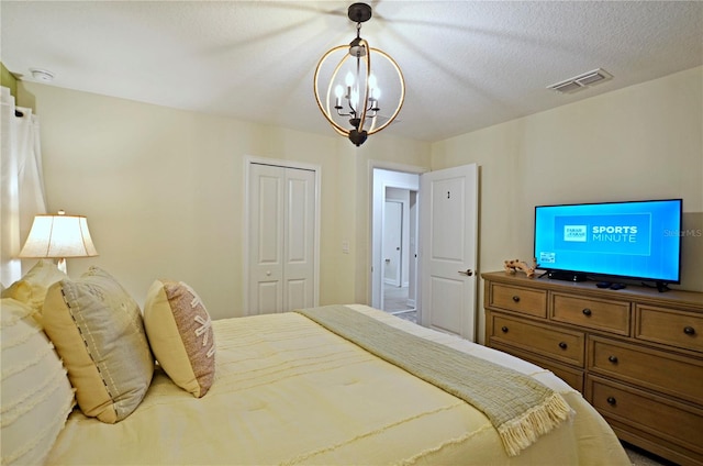 bedroom featuring a notable chandelier, a closet, and a textured ceiling