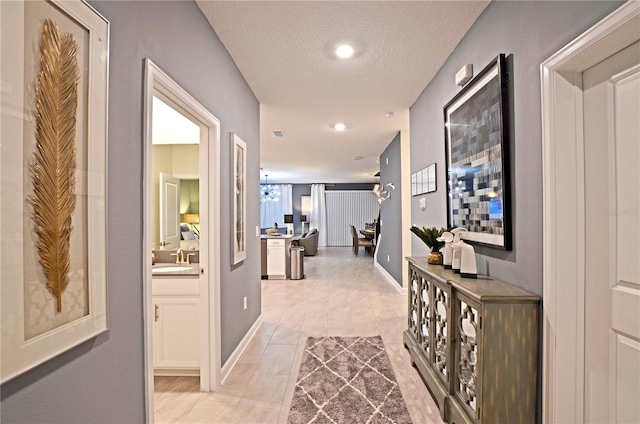 hall featuring light tile patterned floors, sink, and a textured ceiling