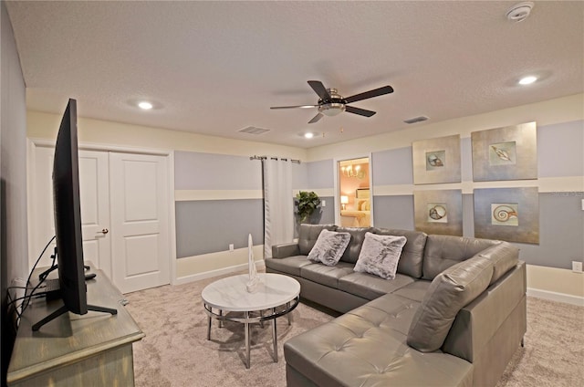 living room with a textured ceiling, ceiling fan, and light colored carpet