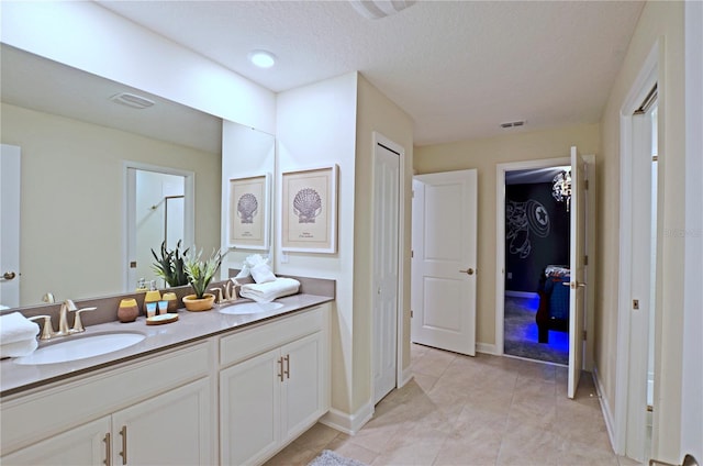 bathroom with dual vanity, a textured ceiling, and tile patterned flooring