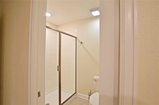 bathroom with toilet, a shower with door, a textured ceiling, and tile patterned flooring