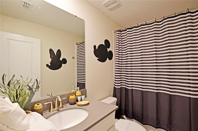 bathroom featuring vanity, a textured ceiling, and toilet