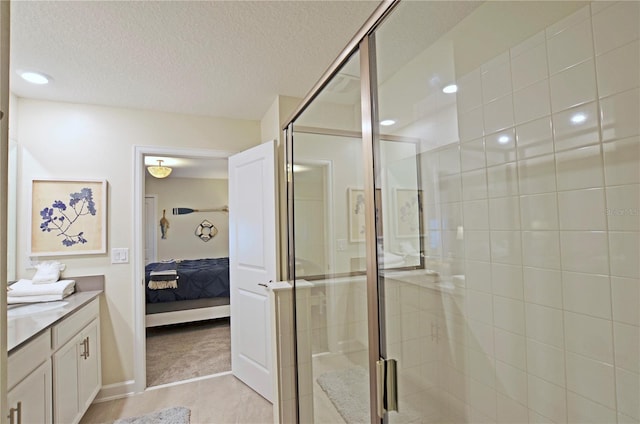 bathroom with tile patterned flooring, a shower with door, vanity, and a textured ceiling