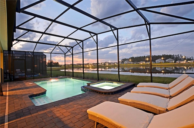 pool at dusk featuring an in ground hot tub, a water view, a patio, and a lanai