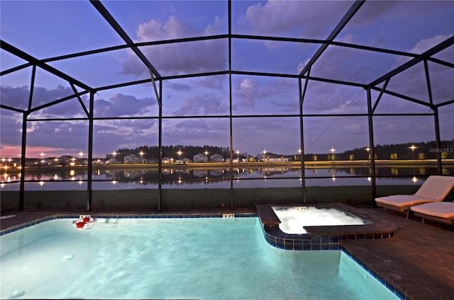 pool at dusk with an in ground hot tub and a lanai