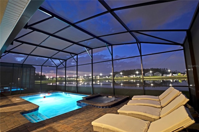 pool at dusk featuring an in ground hot tub, a patio area, and a lanai