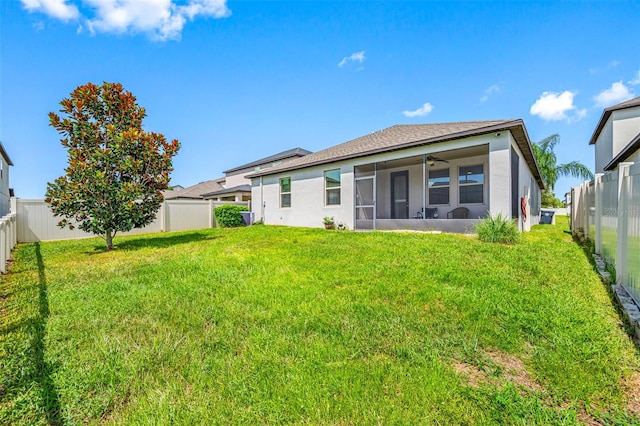 rear view of property featuring a yard and a sunroom