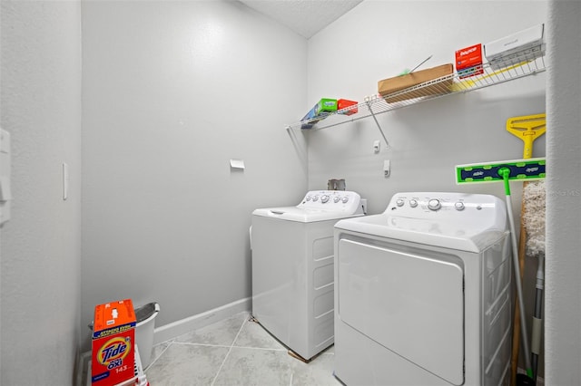 laundry room with washing machine and dryer, a textured ceiling, and light tile patterned floors