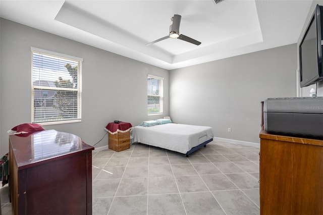 tiled bedroom featuring a raised ceiling and ceiling fan