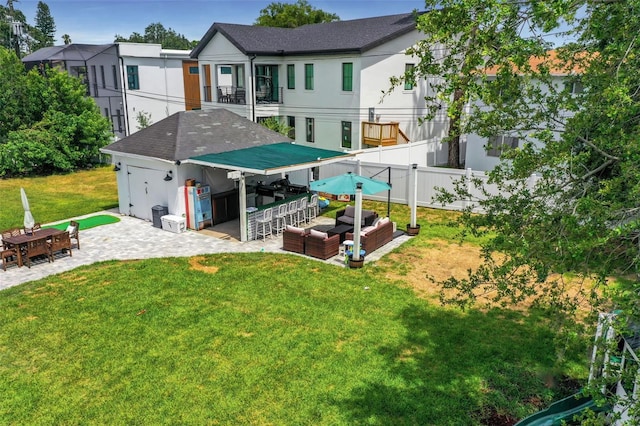 rear view of property featuring an outdoor living space, a patio, a yard, and exterior bar