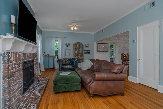 living room with ceiling fan, a fireplace, crown molding, and hardwood / wood-style flooring