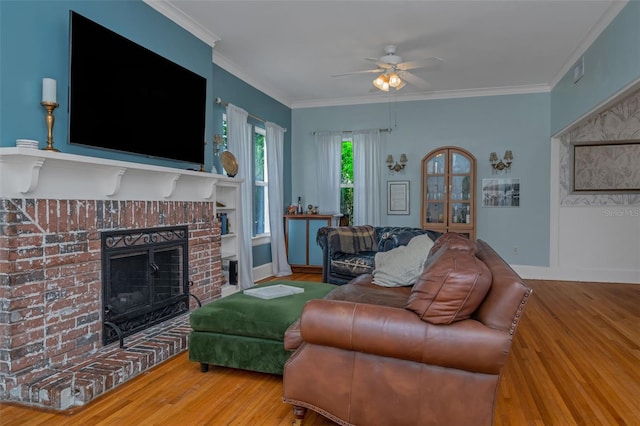 living room with ceiling fan, a brick fireplace, crown molding, and hardwood / wood-style floors