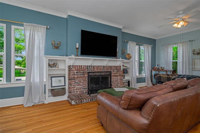 living room with ceiling fan, a fireplace, crown molding, and light hardwood / wood-style floors