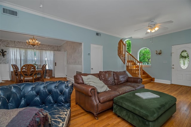 living room with ceiling fan with notable chandelier, wood-type flooring, and crown molding