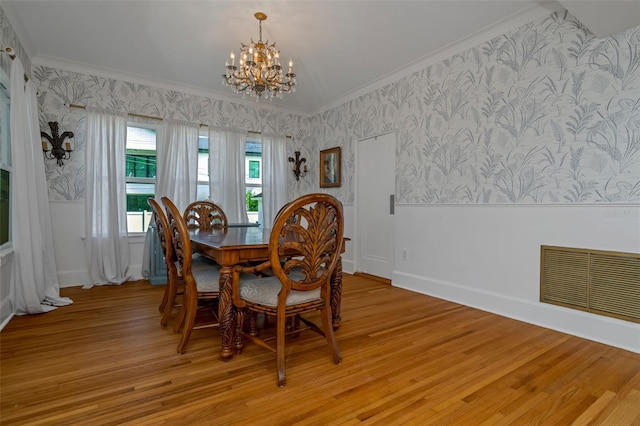 dining room with an inviting chandelier, ornamental molding, and light hardwood / wood-style flooring